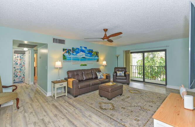 A living room with a brown leather sofa, matching ottoman, area rug, and balcony access — 150 Pineview Road # L6, Jupiter FL 33469, JUPITER, FL