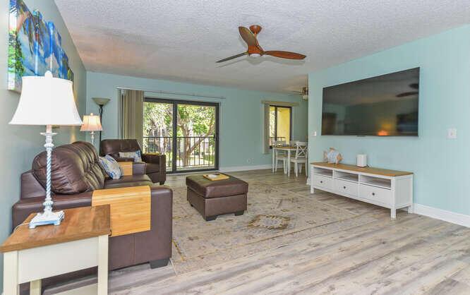 A living room features a brown leather sofa, matching ottoman, television, and light blue walls — 150 Pineview Road # L6, Jupiter FL 33469, JUPITER, FL