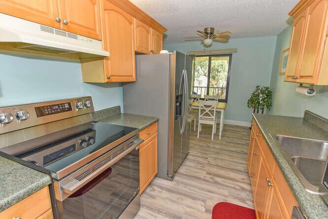A kitchen with light wood cabinets, stainless steel appliances, and a dining area beyond — 150 Pineview Road # L6, Jupiter FL 33469, JUPITER, FL