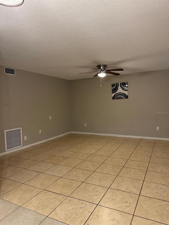 An empty room with beige tile flooring, light-colored walls, and a ceiling fan — 6080 22ND AVENUE N UNIT 5, ST PETERSBURG, FL