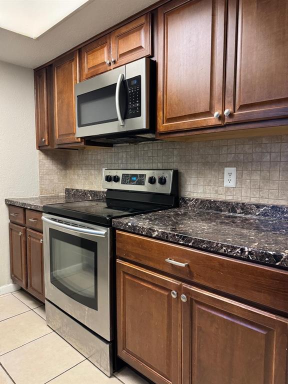 A kitchen features dark wood cabinets, stainless steel appliances, and a dark granite countertop — 6080 22ND AVENUE N UNIT 5, ST PETERSBURG, FL