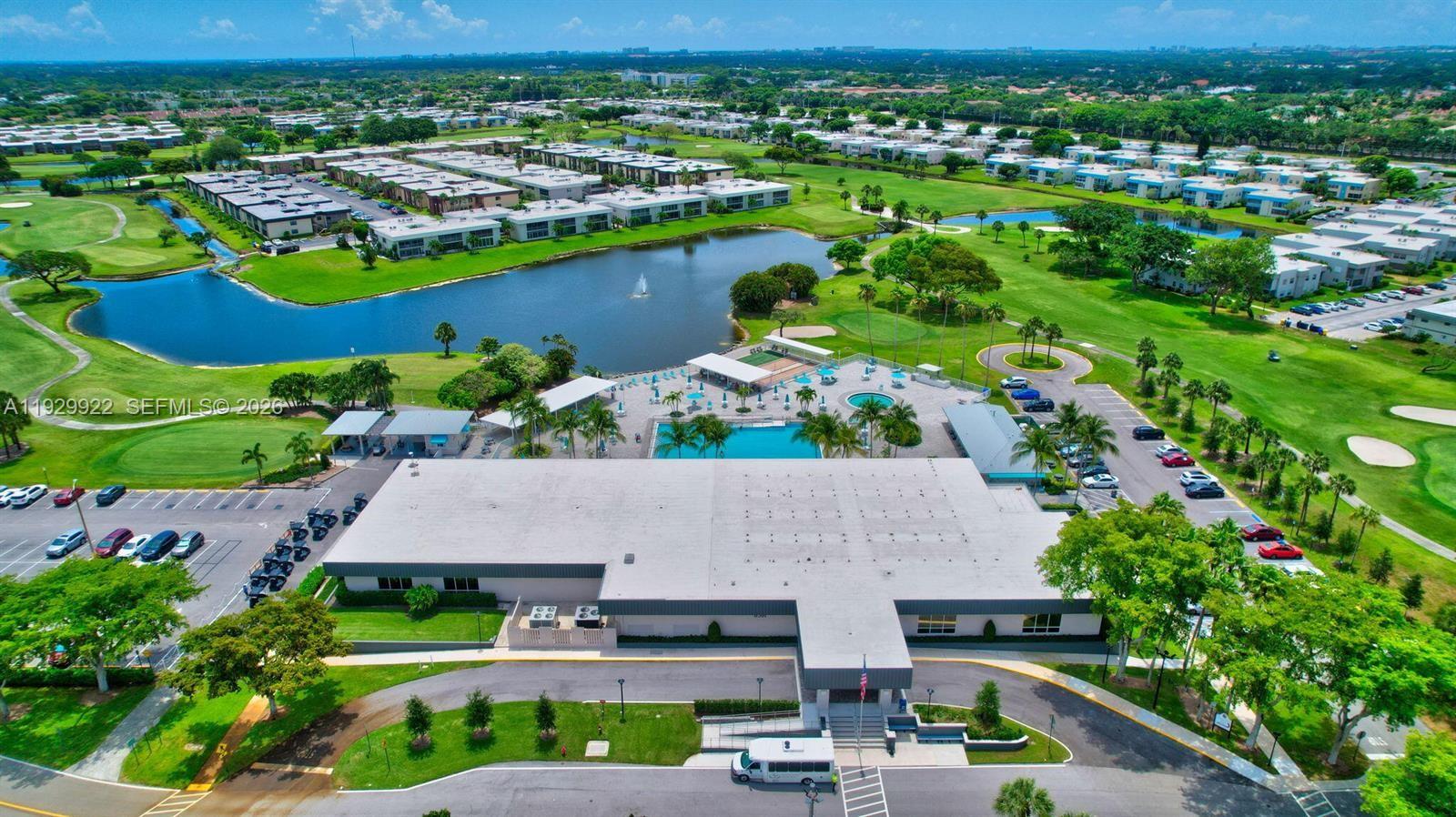 An aerial view shows a large clubhouse with a pool, parking lots, and surrounding golf course — 25 Saxony A # A, Delray Beach FL 33446, DELRAY BEACH, FL