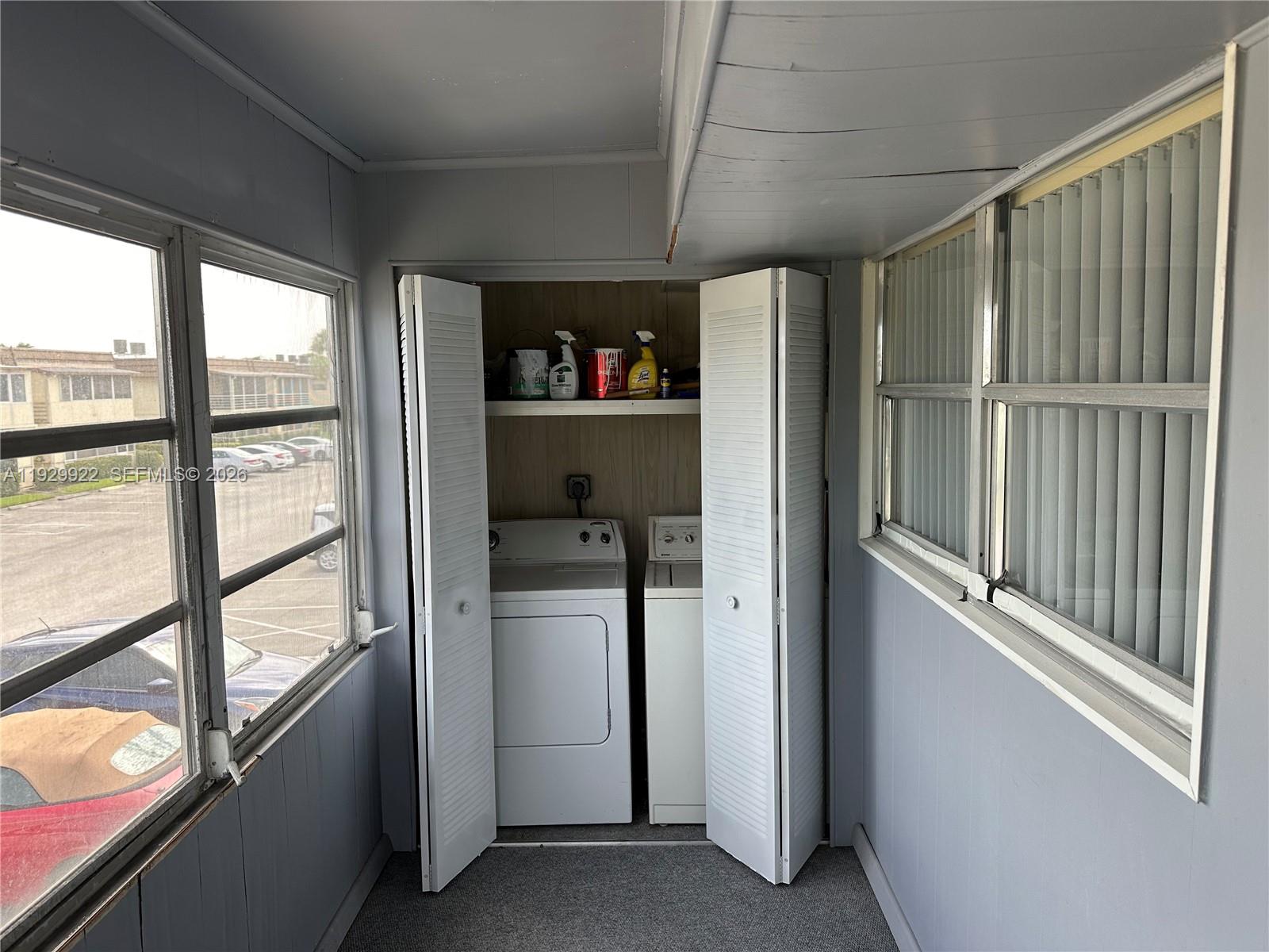 A laundry closet with a washer and dryer is located in a sunroom with windows — 25 Saxony A # A, Delray Beach FL 33446, DELRAY BEACH, FL