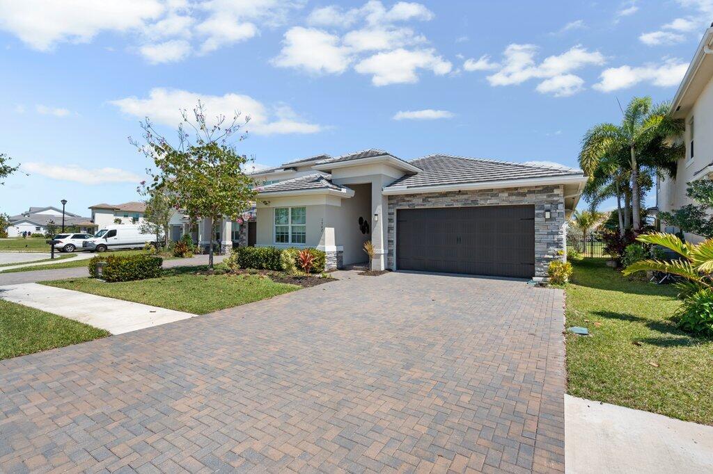 A single-story house with a stone facade, a two-car garage, and a paved driveway — 1362 Harvester Crossing, Loxahatchee FL 33470, LOXAHATCHEE, FL