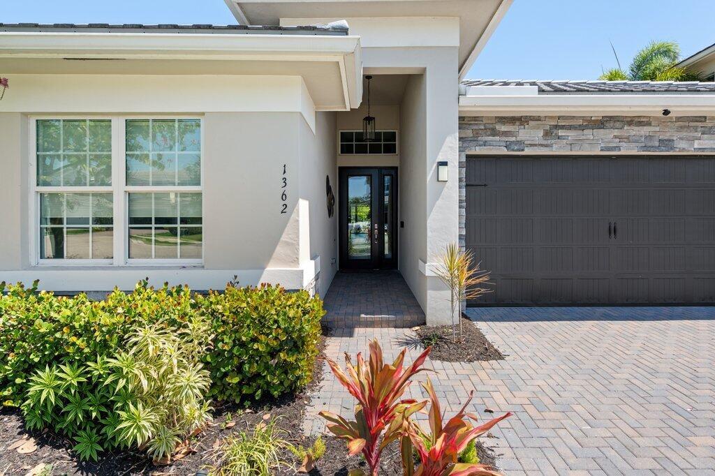 A modern house exterior featuring a paved driveway, a garage, and a covered entryway — 1362 Harvester Crossing, Loxahatchee FL 33470, LOXAHATCHEE, FL