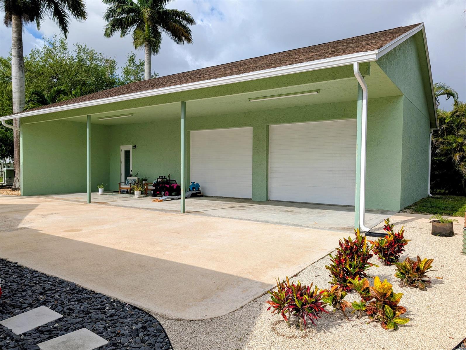 A light green detached garage with a covered patio, two white doors, and a concrete driveway — 8763 Pinion Drive, Lake Worth FL 33467, LAKE WORTH, FL