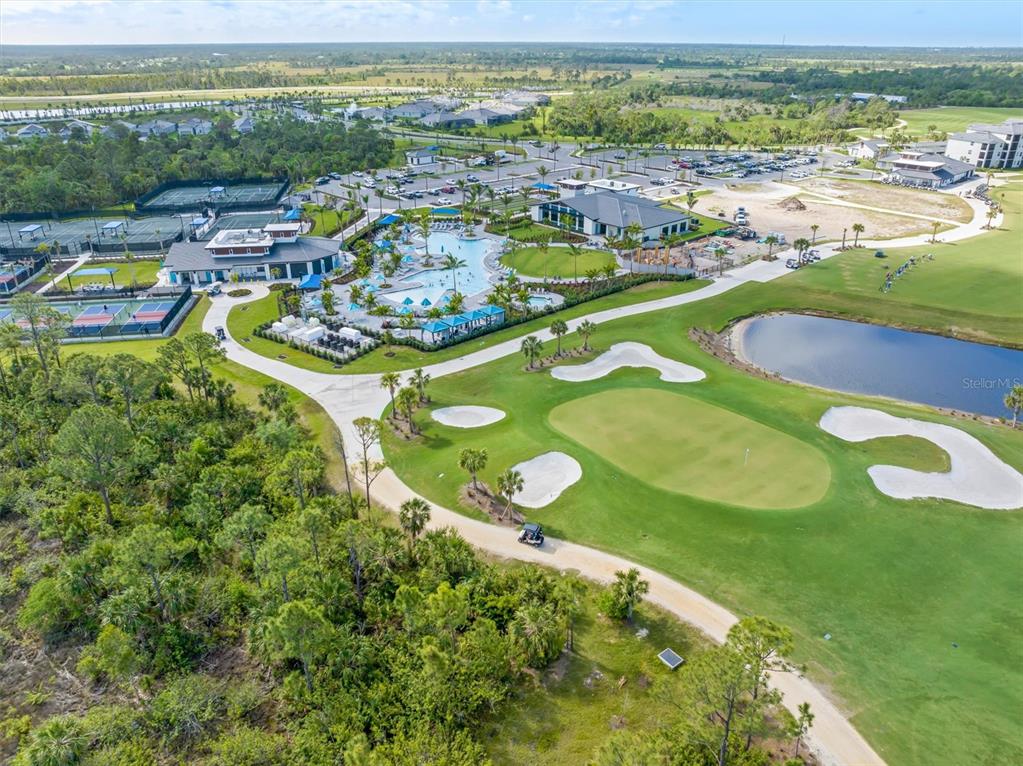An aerial view shows a community clubhouse with a pool, tennis courts, and a golf course — 17475 OPAL SAND DRIVE UNIT 205, VENICE, FL