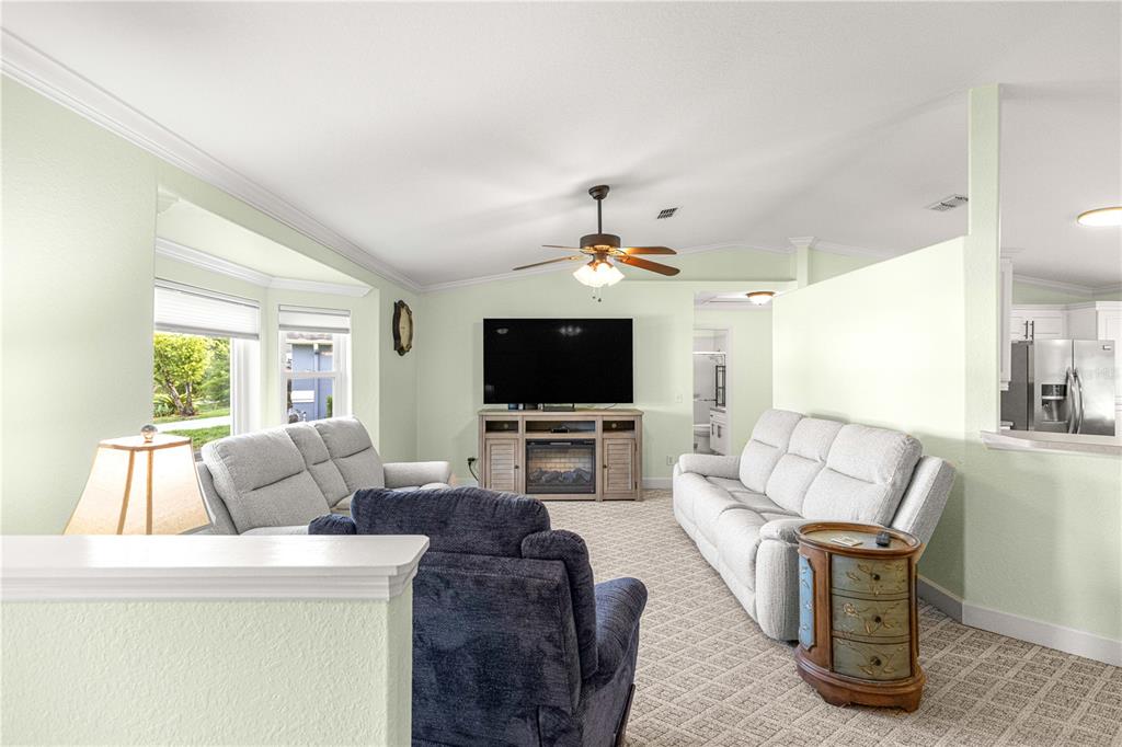 A living room features light green walls, carpeted floors, a ceiling fan, and two sofas — 5968 SW 103 LOOP, OCALA, FL