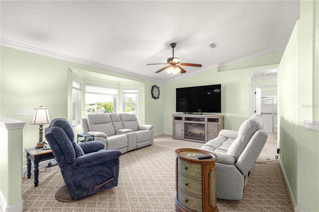 A living room features light green walls, carpeted floors, a ceiling fan, and a television console — 5968 SW 103 LOOP, OCALA, FL