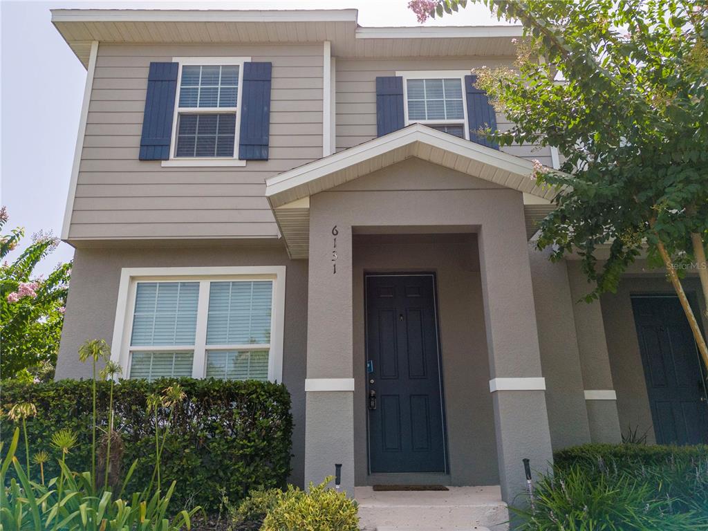 A two-story house exterior features gray siding, blue shutters, and a covered front entryway — 6131 ELFIN HERB WAY, WINTER GARDEN, FL