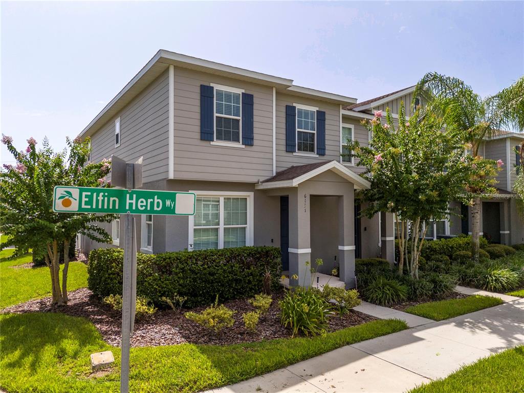 A two-story suburban house with gray siding and a street sign in the foreground — 6131 ELFIN HERB WAY, WINTER GARDEN, FL