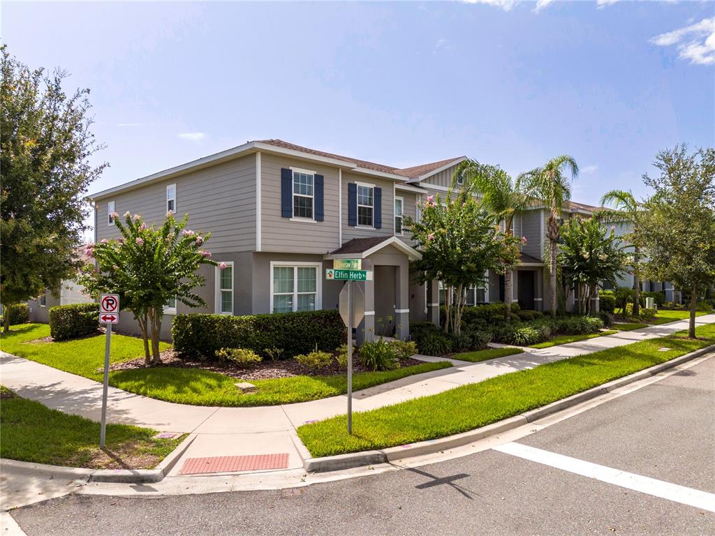 A two-story townhouse with gray siding and blue shutters sits on a corner lot — 6131 ELFIN HERB WAY, WINTER GARDEN, FL