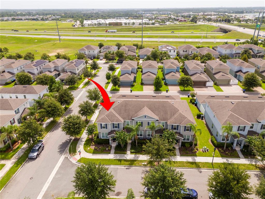 An aerial view shows a multi-unit residential building with a red arrow pointing toward it — 6131 ELFIN HERB WAY, WINTER GARDEN, FL