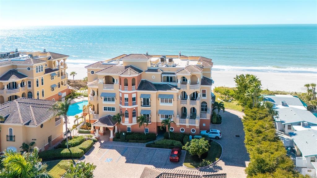 An aerial view shows a multi-story tan apartment building near a beach and ocean — 4127 GULF OF MEXICO DRIVE UNIT N102, LONGBOAT KEY, FL