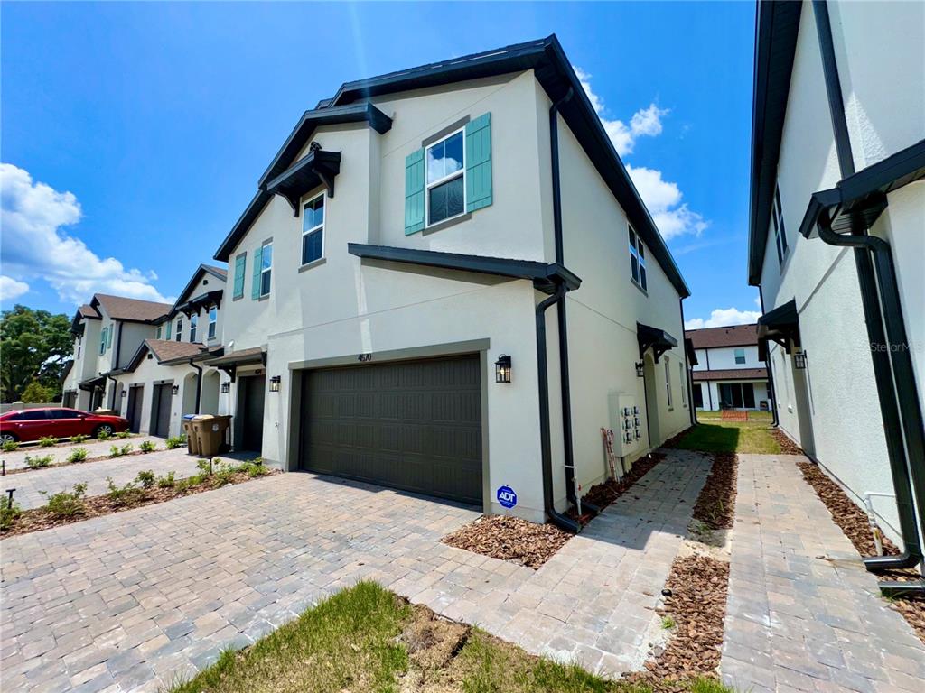 A two-story townhouse exterior with a paved driveway, garage, and light-colored stucco siding — 4570 SMALL CREEK ROAD, KISSIMMEE, FL