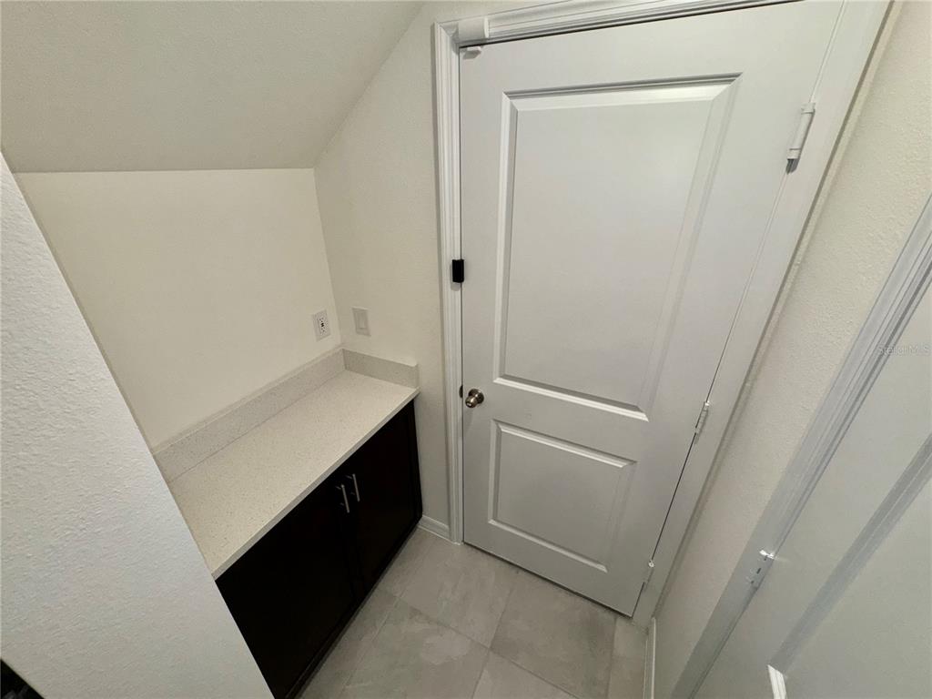 A small nook features a dark wood cabinet with a light countertop beside a door — 4570 SMALL CREEK ROAD, KISSIMMEE, FL