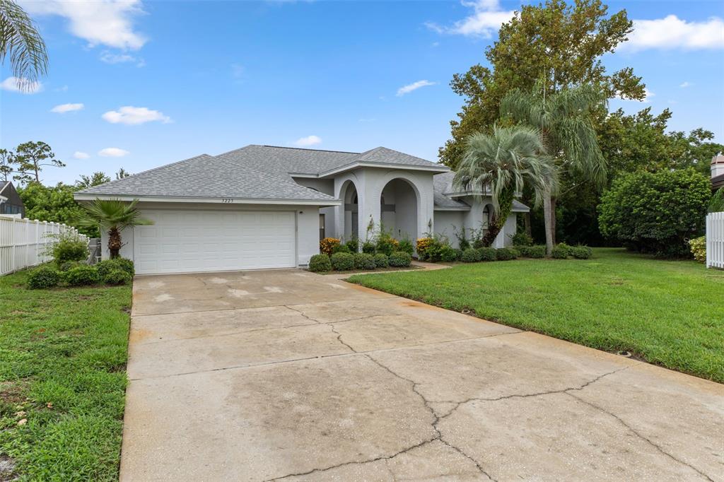 A single-story house with a white garage, arched entryway, and a cracked concrete driveway — 3225 GLENWOOD CIRCLE, HOLIDAY, FL