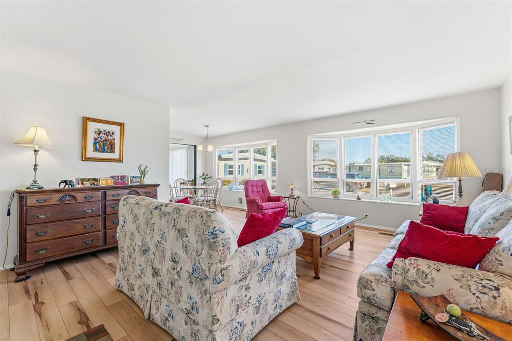 A living room features floral sofas, a wooden dresser, and large windows with natural light — 6581 HONU COURT, NORTH PORT, FL