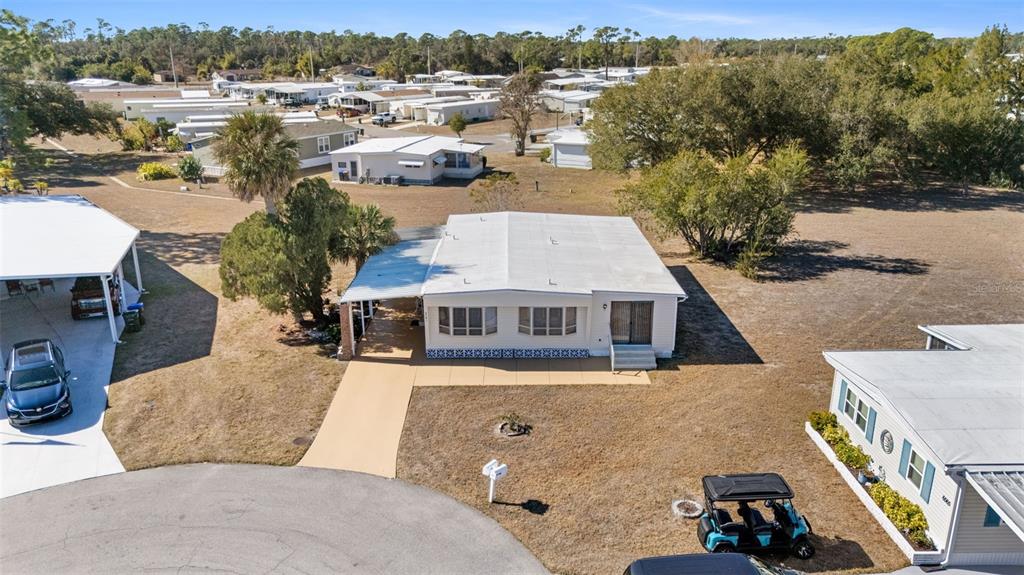 An aerial view shows a single-story mobile home with a carport and a golf cart — 6581 HONU COURT, NORTH PORT, FL
