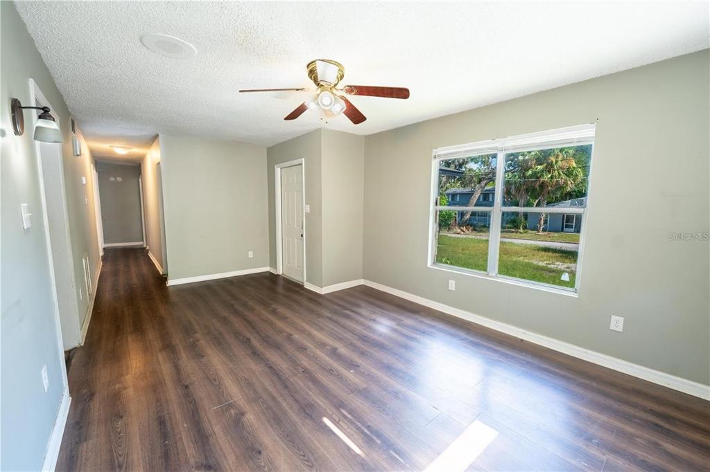 An empty room features wood-look flooring, light green walls, a ceiling fan, and a window — 535 W DIVISION STREET, DELAND, FL