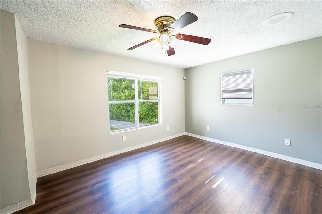 An empty room features wood-look flooring, light-colored walls, a ceiling fan, and two windows — 535 W DIVISION STREET, DELAND, FL