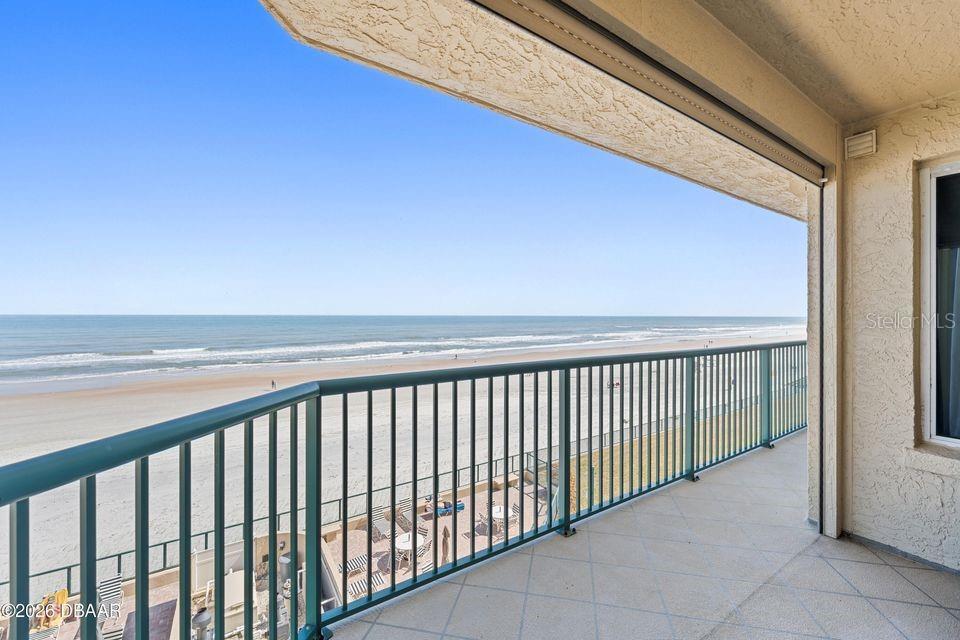 A balcony with a green metal railing overlooks a sandy beach and the ocean — 4575 S ATLANTIC AVENUE UNIT 6303, PORT ORANGE, FL