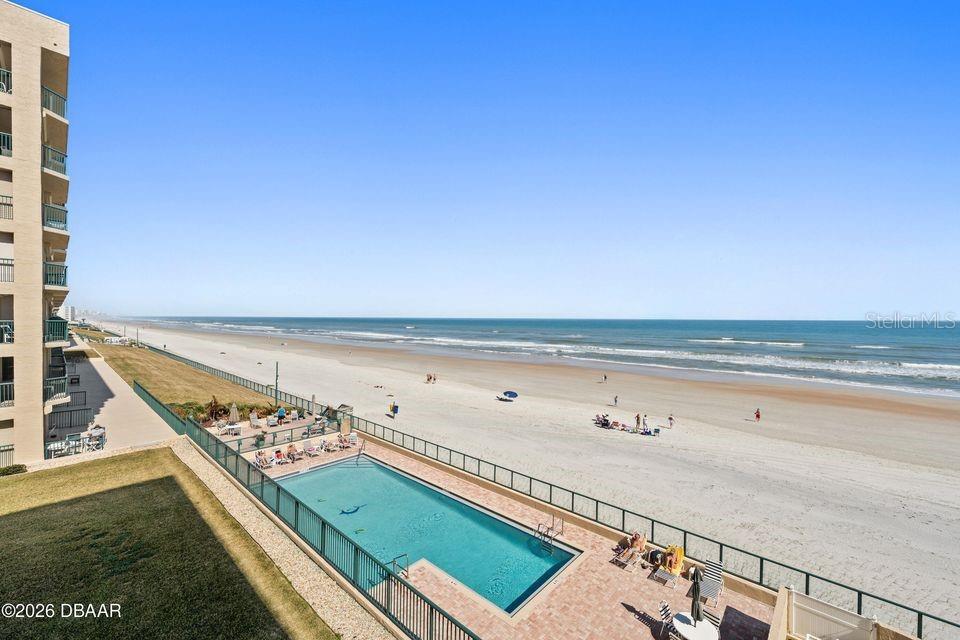 An elevated view of a swimming pool located on a sandy beach beside a building — 4575 S ATLANTIC AVENUE UNIT 6303, PORT ORANGE, FL