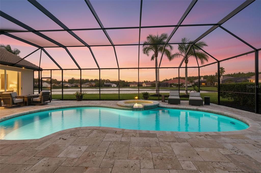 A swimming pool and spa are enclosed by a screen cage overlooking a lake — 4618 AVENUE LONGCHAMPS, LUTZ, FL