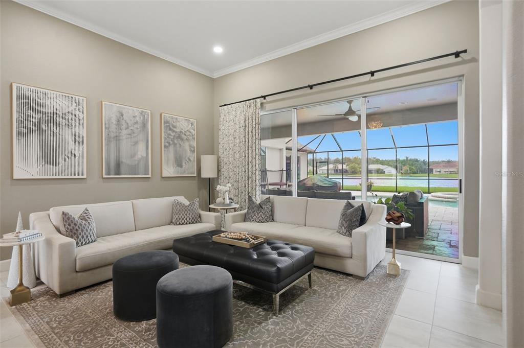 A living room features a white sofa, a black tufted ottoman, and a marble fireplace — 4618 AVENUE LONGCHAMPS, LUTZ, FL