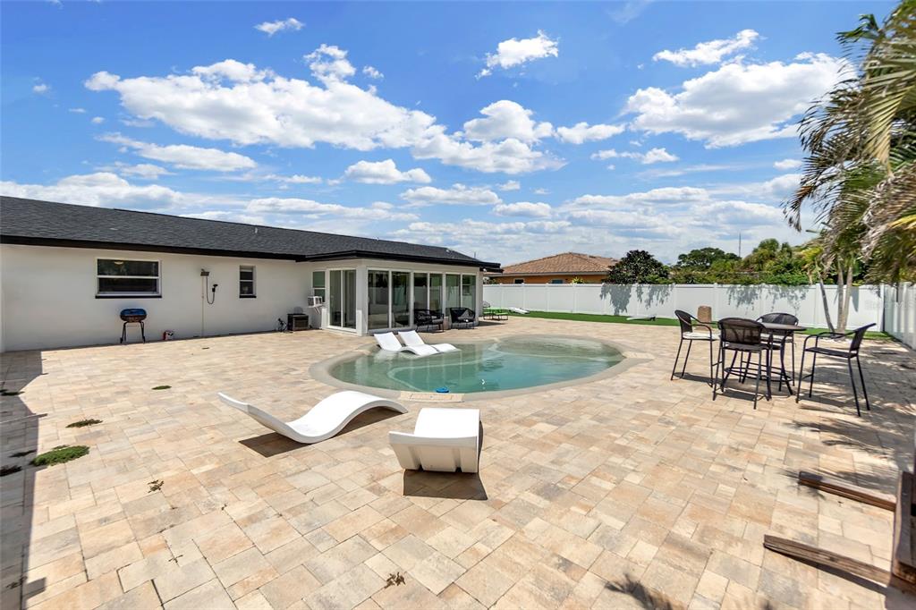 A backyard features a paved patio, a small kidney-shaped pool, and outdoor furniture — 7221 15TH AVENUE DRIVE W, BRADENTON, FL