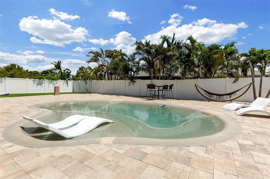 A backyard features a swimming pool with lounge chairs, a hammock, and a dining set — 7221 15TH AVENUE DRIVE W, BRADENTON, FL