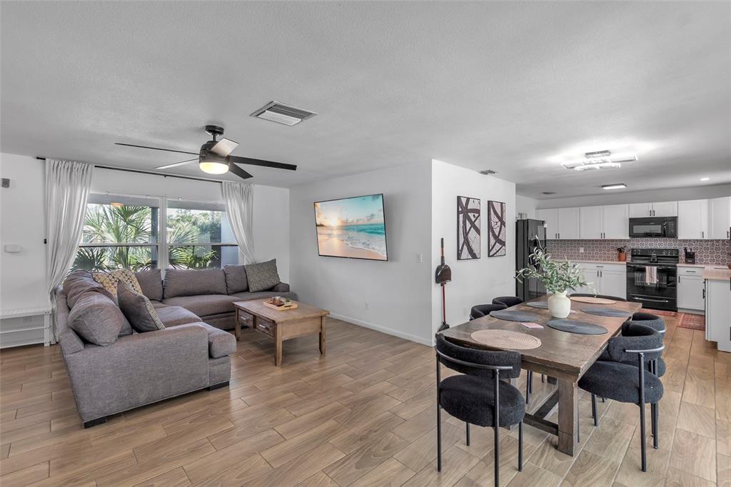 An open-concept living and dining area features wood-look tile flooring and a modern kitchen — 7221 15TH AVENUE DRIVE W, BRADENTON, FL