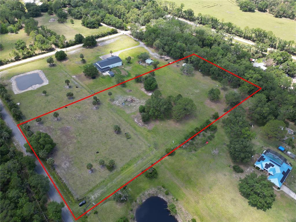 An aerial view shows a large, rectangular plot of land outlined in red — 1234 QUAIL RUN, OSTEEN, FL