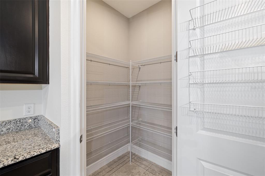 A kitchen features dark wood cabinets, granite countertops, stainless steel appliances, and a central island — 3910 REDFIN PLACE, KISSIMMEE, FL