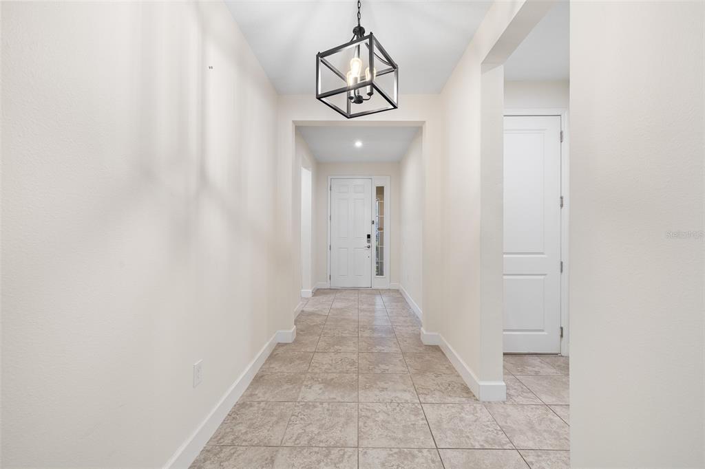A sunroom features light-colored tile flooring, a ceiling fan, and large windows overlooking a yard — 3910 REDFIN PLACE, KISSIMMEE, FL