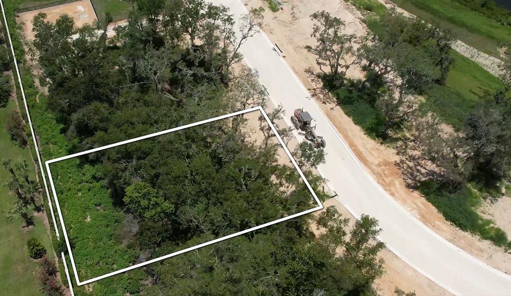 An aerial view shows a wooded residential lot outlined in white next to a paved road — 146 TRANQUIL MIRROR LAKE COURT Lot 19, CLERMONT, FL