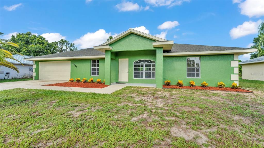A bright green single-story house features a two-car garage, a covered entryway, and landscaped beds — 4515 STARFISH AVENUE, SEBRING, FL