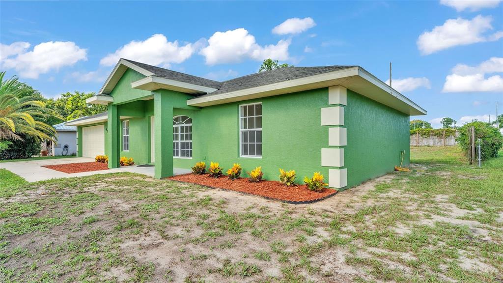 A bright green single-story house with a white-trimmed corner and a front-facing garage — 4515 STARFISH AVENUE, SEBRING, FL