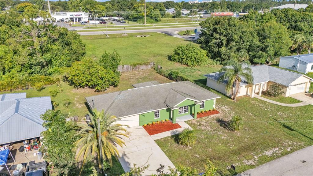 An aerial view shows a green single-story house with a driveway and surrounding grassy yard — 4515 STARFISH AVENUE, SEBRING, FL