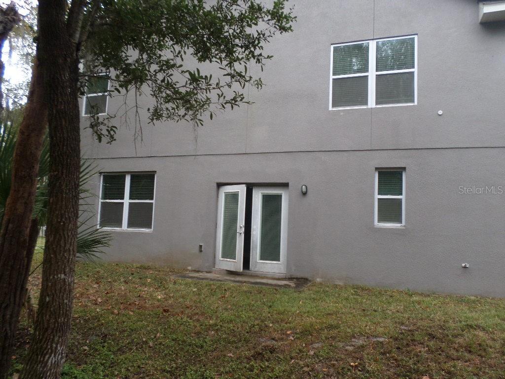 The exterior of a two-story gray stucco house features a set of double glass doors — 2773 RED WING VILLAGE, DELAND, FL
