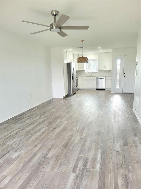 An open-concept living and kitchen area features light wood-look flooring and a ceiling fan — 957 SANDPIPER CIRCLE UNIT 0, BRADENTON, FL