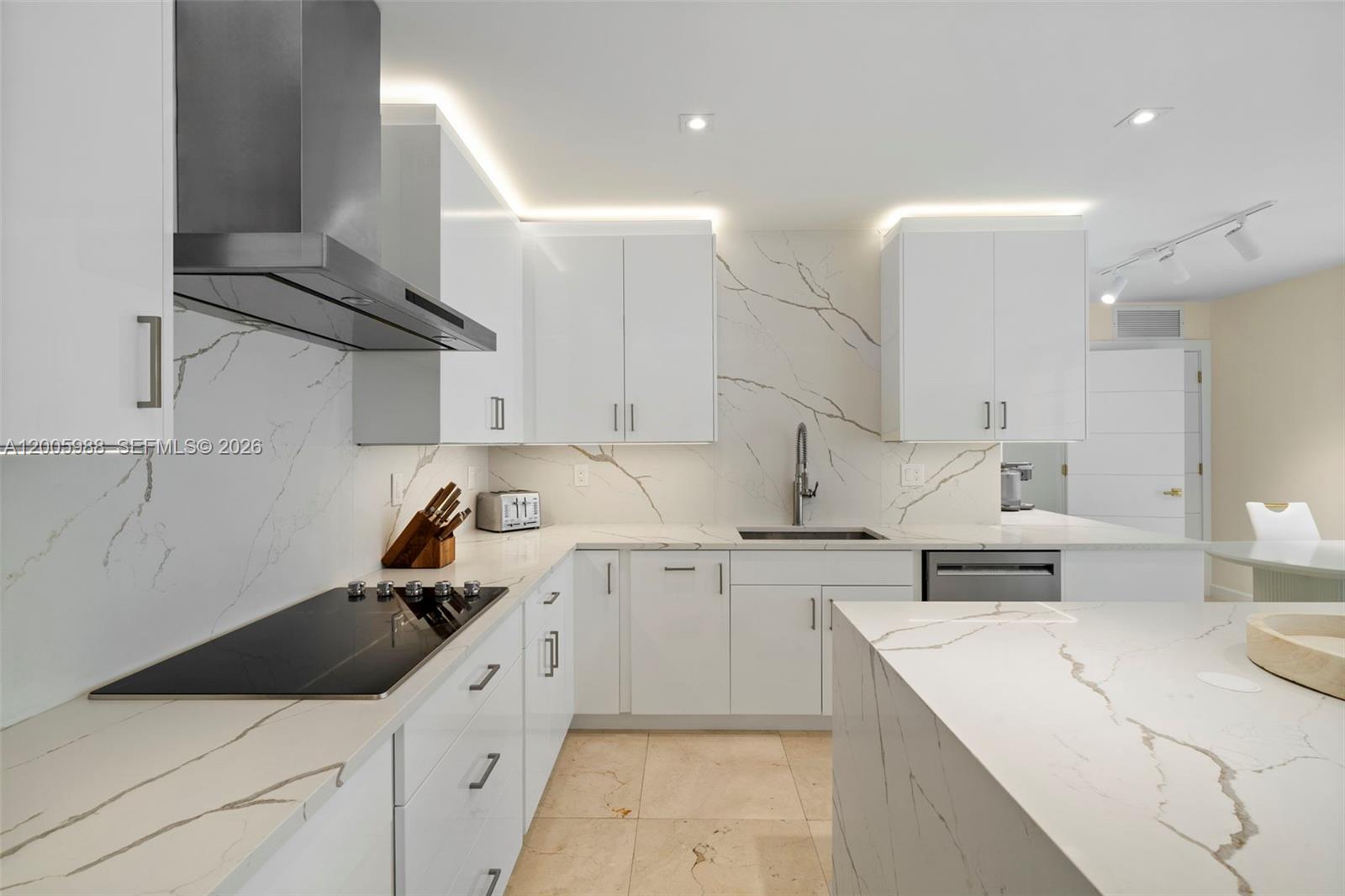 A modern kitchen features white cabinetry, marble-patterned countertops and backsplash, and stainless steel appliances — 1830 S Ocean Dr # 5103, Hallandale Beach FL 33009, HALLANDALE BEACH, FL