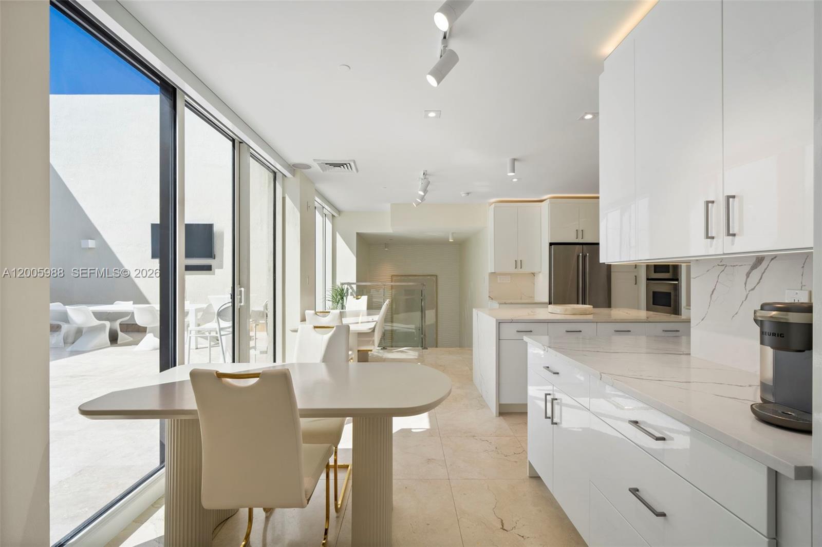 A modern kitchen and dining area features white cabinetry, marble countertops, and a glass patio door — 1830 S Ocean Dr # 5103, Hallandale Beach FL 33009, HALLANDALE BEACH, FL