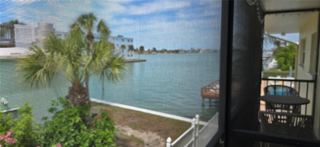 A view of a waterfront canal from a screened-in balcony with outdoor furniture — 175 55TH AVENUE UNIT 204, ST PETE BEACH, FL