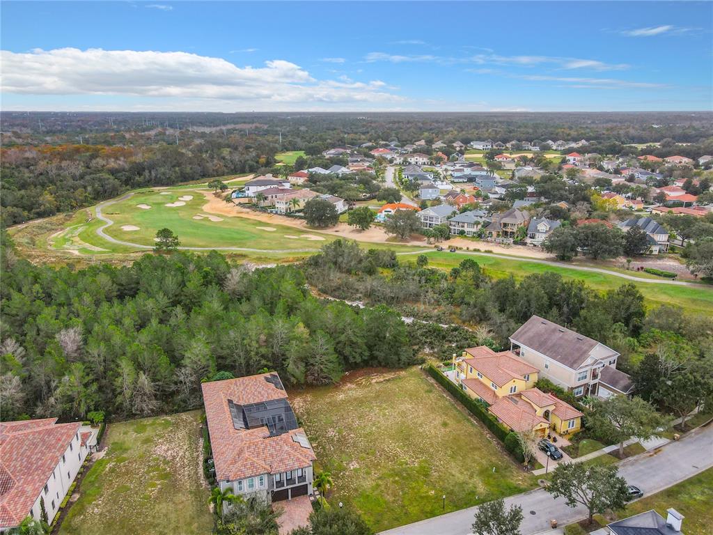 An aerial view shows a vacant residential lot situated between two houses near a golf course — 1113 WATSON COURT, KISSIMMEE, FL