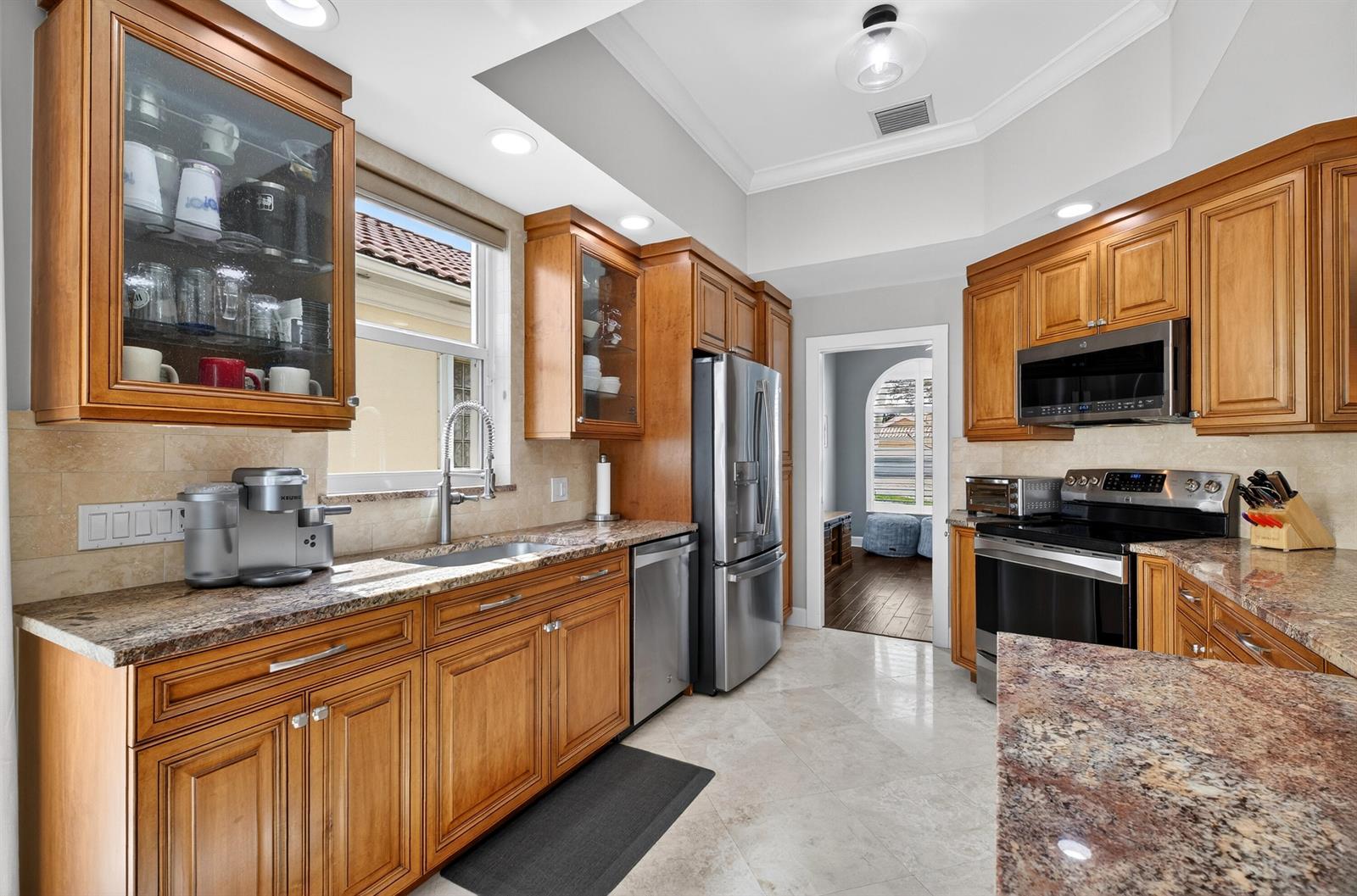 A kitchen features wood cabinets, granite countertops, stainless steel appliances, and tile flooring — 8223 Pine Cay Road, Wellington FL 33414, WELLINGTON, FL