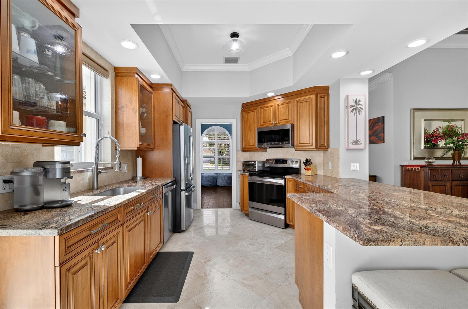 A kitchen features wood cabinets, granite countertops, stainless steel appliances, and tile flooring — 8223 Pine Cay Road, Wellington FL 33414, WELLINGTON, FL