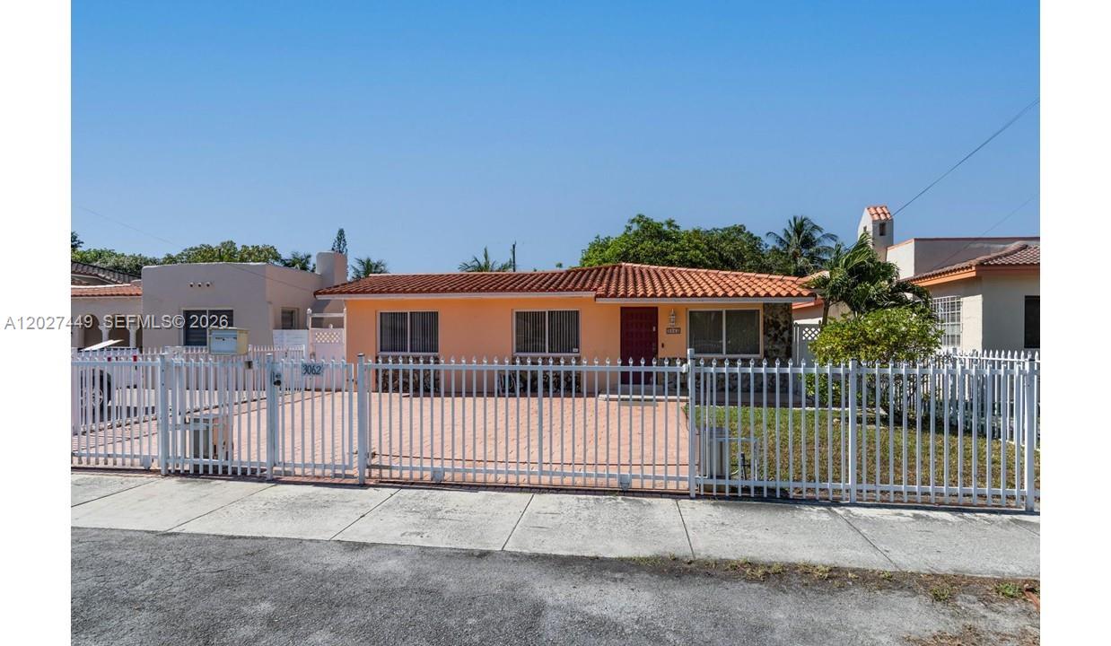 A single-story peach-colored house with a tiled roof sits behind a white metal fence — 3062 SW 14th St, Miami FL 33145, MIAMI, FL