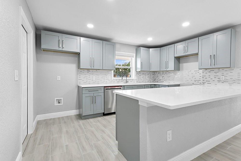A kitchen with light gray cabinets, white countertops, a tile backsplash, and light wood-look flooring — 4823 KATHY JO TERRACE, ORLANDO, FL