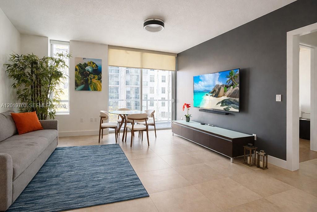 A living room features a gray accent wall, a television, a dining set, and tile flooring — 1050 Brickell Ave # 2210, Miami FL 33131, MIAMI, FL